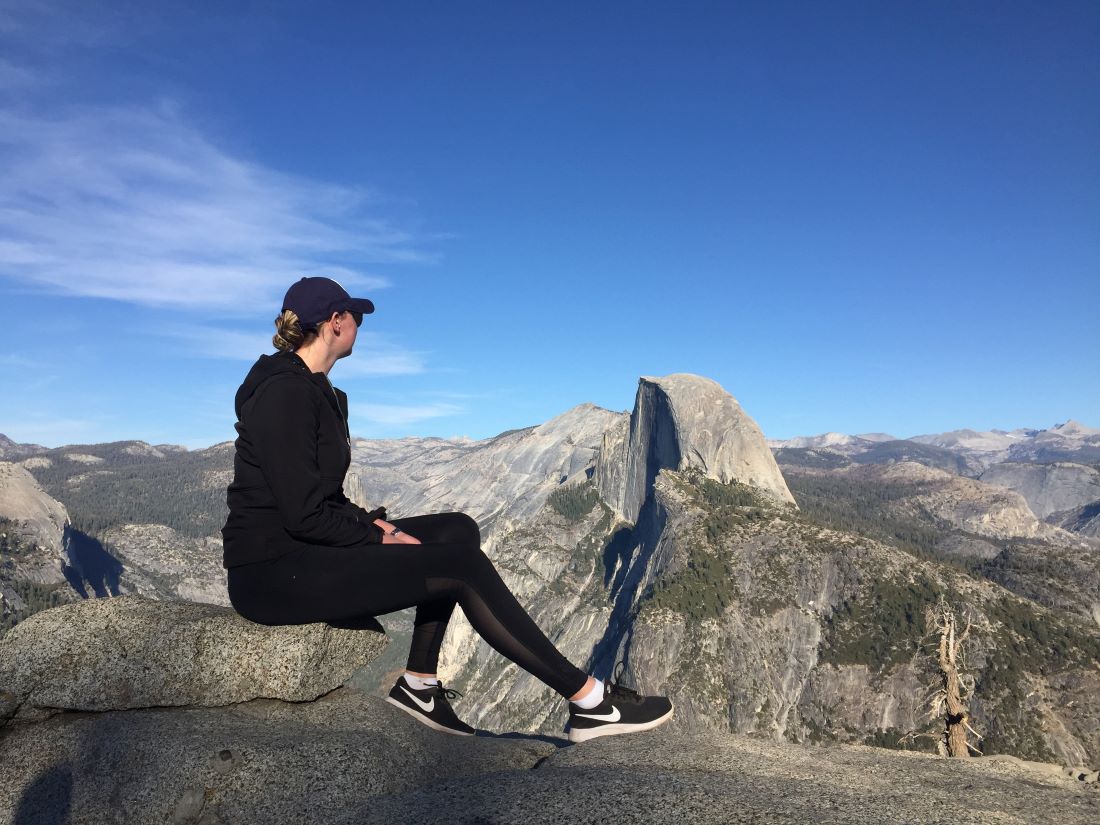 Caitlin Burns sits on a rocky summit at Glacier Point in Yosemite National Park
