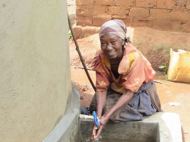 A woman in Bugluube Village Nakakawa smiling as she runs water over her hands | Just a Drop