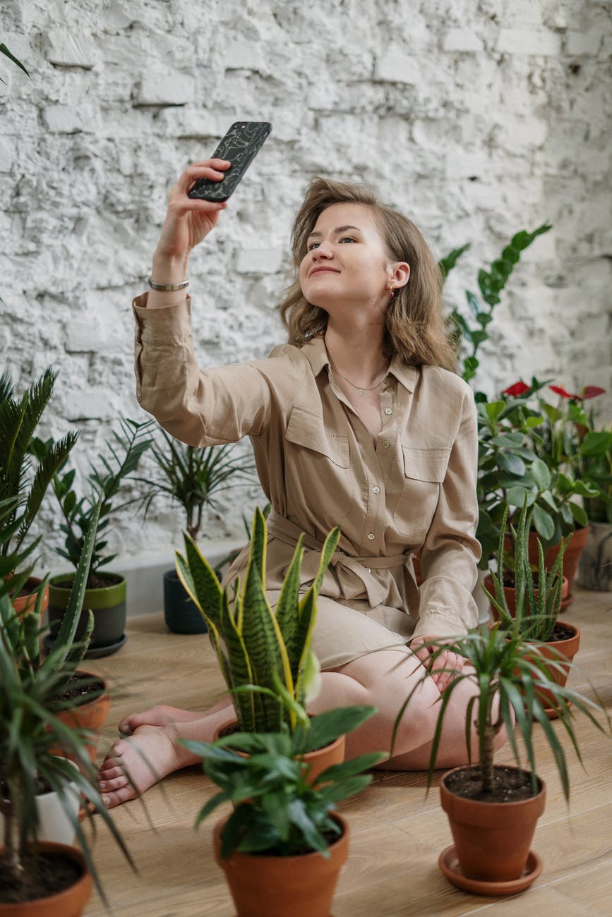 woman in brown button up long sleeve shirt taking selfie using smartphone