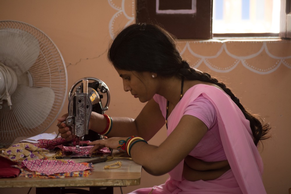 woman in a pink sari working on a sewing machine at the Sambhali Trust in Rajasthan during a Purposeful Nomad trip with Wanderful