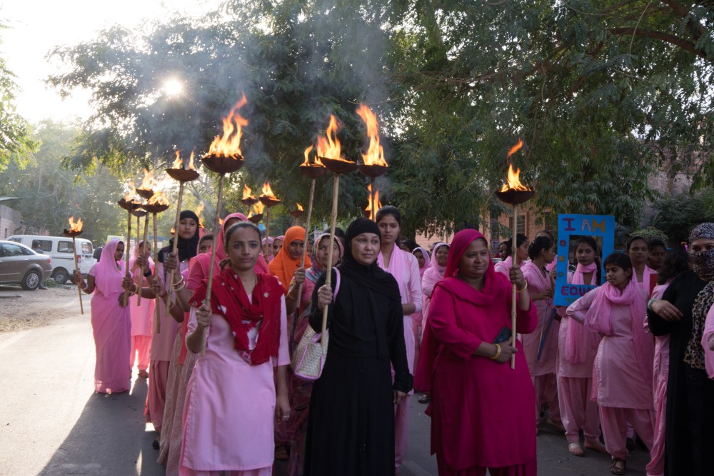 Women of Rajasthan in pink saris carrying torches for women\'s rights